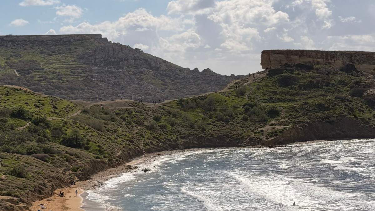 Fale przy piaszczystej plaży otoczonej wzgórzami na Malcie